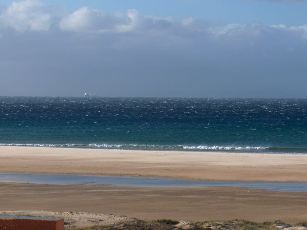 Viento de tierra soplando sobre el mar en una playa, con la superficie del agua rizada y la espuma arrastrada mar adentro