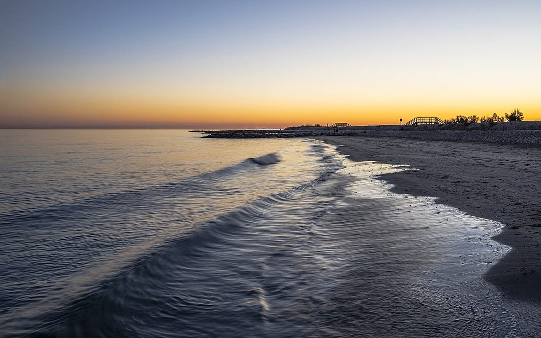 Atardecer dorado sobre una playa casi vacía, una de las mejores horas para ir a la playa
