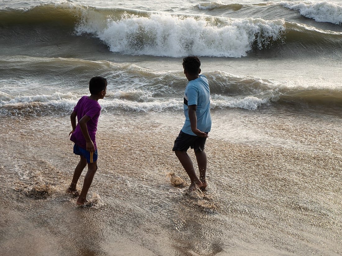 Niños observando de cerca las olas en la orilla del mar, escena ligada a la seguridad de los niños en la playa
