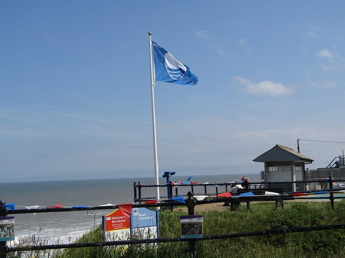 Bandera Azul ondeando en su mástil junto al mar