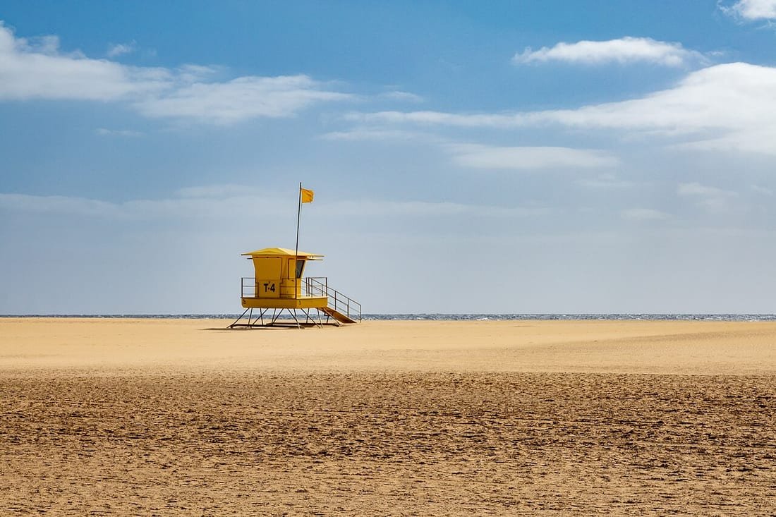 Torre de vigilancia de socorristas en una playa española con el mástil de banderas al lado